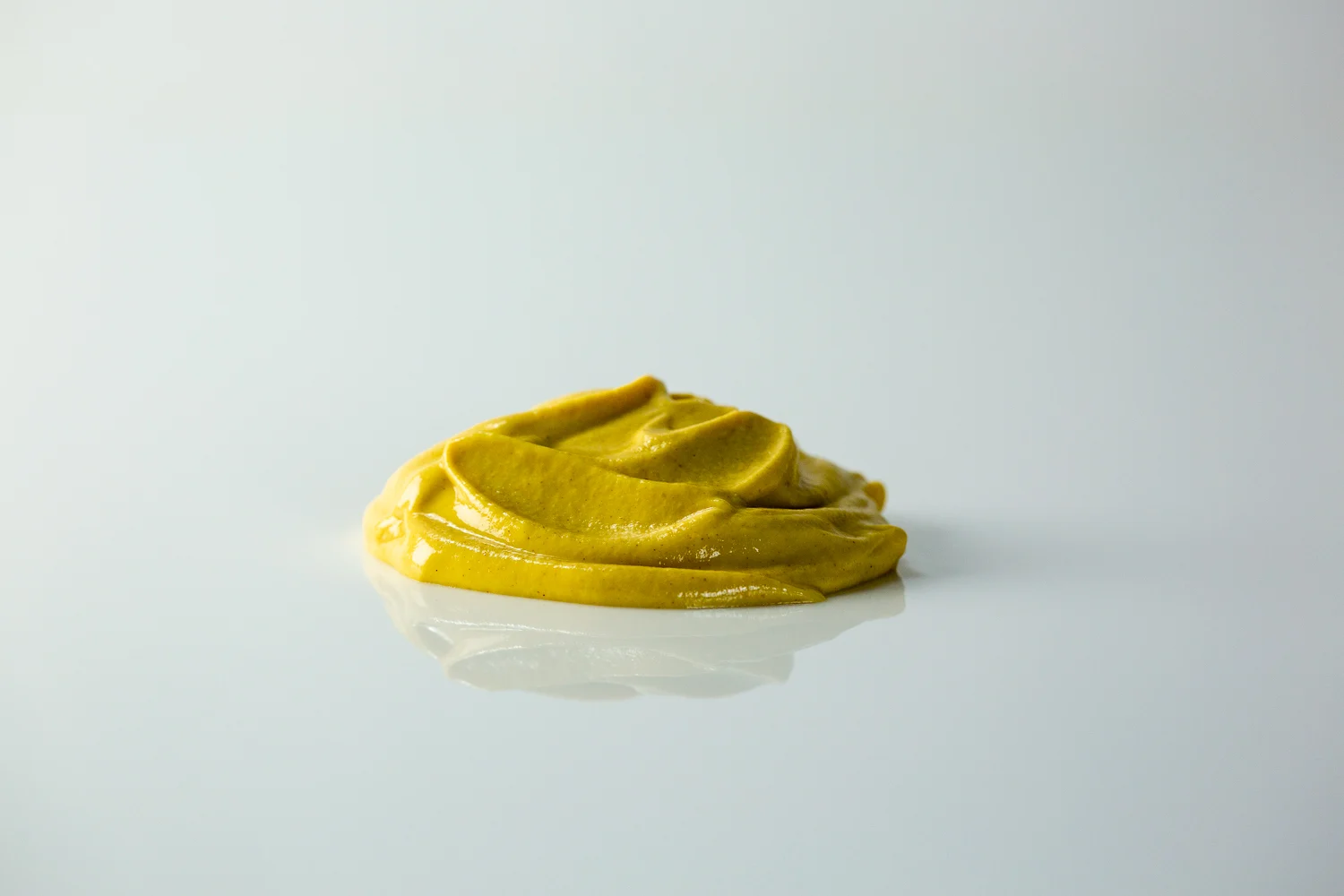 a pile of yellowish brown mustard on a white background