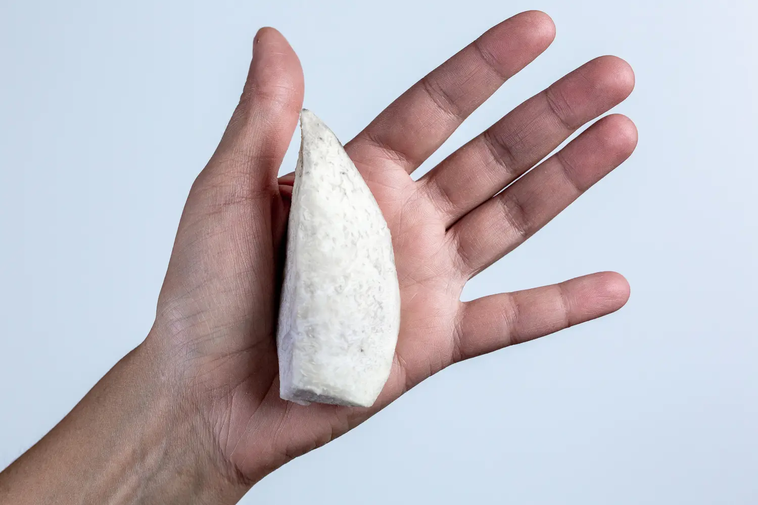 a hand holding a large cooked taro wedge for babies 6 mos+