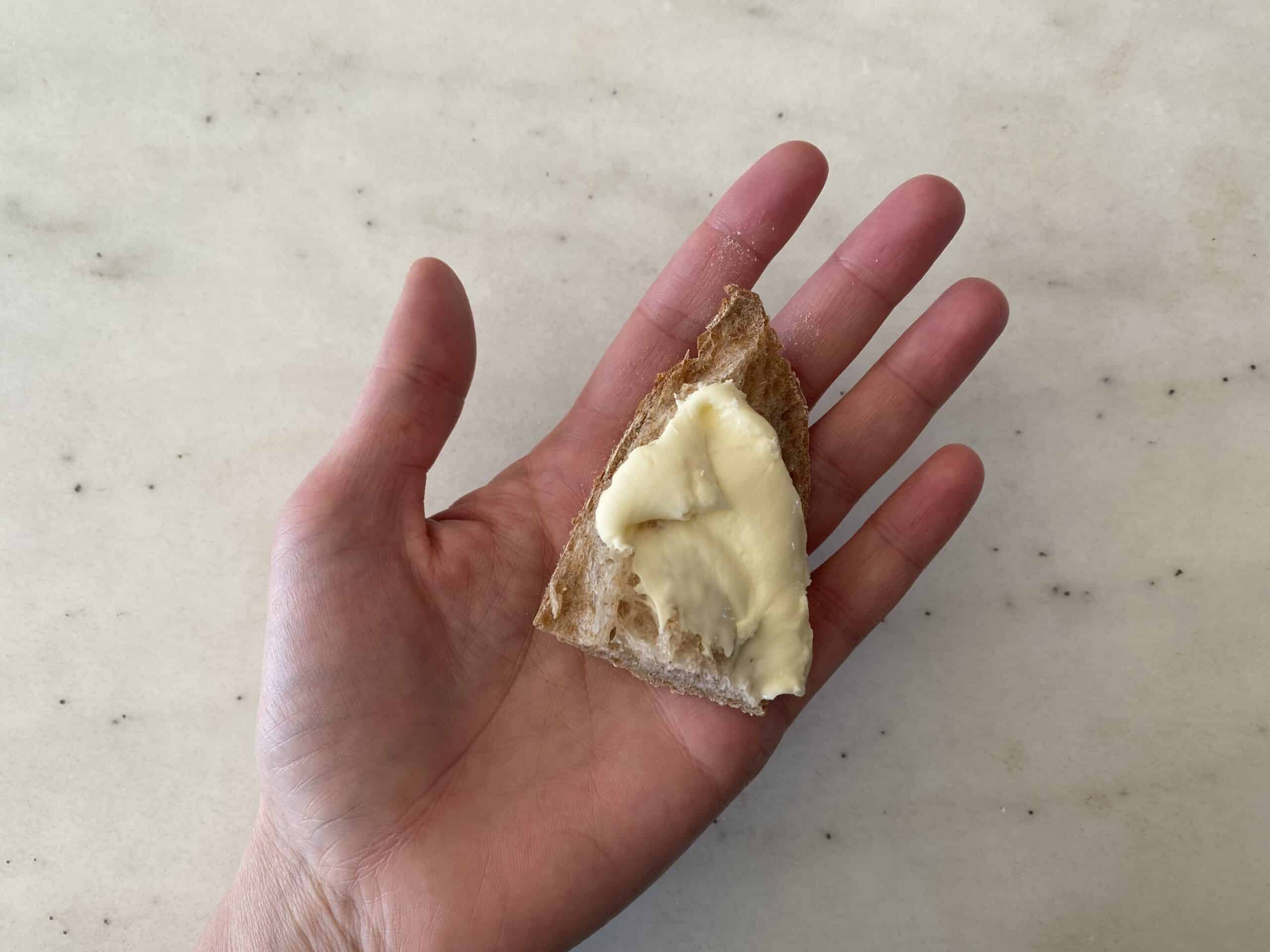 a hand holding cooked brie spread on toast