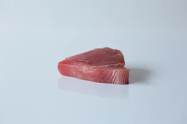 a raw cut of tuna steak on a white background
