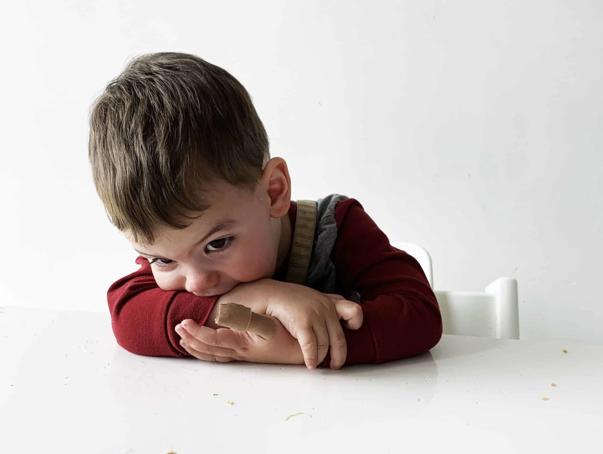 A toddler puts his head down on a table at a meal