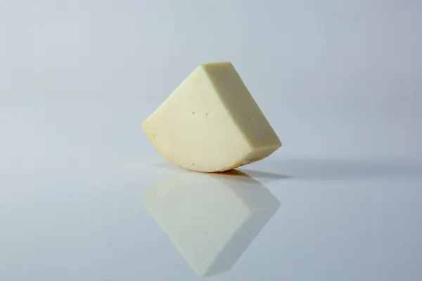 Un pedazo triangular de Provolone sobre un fondo blanco