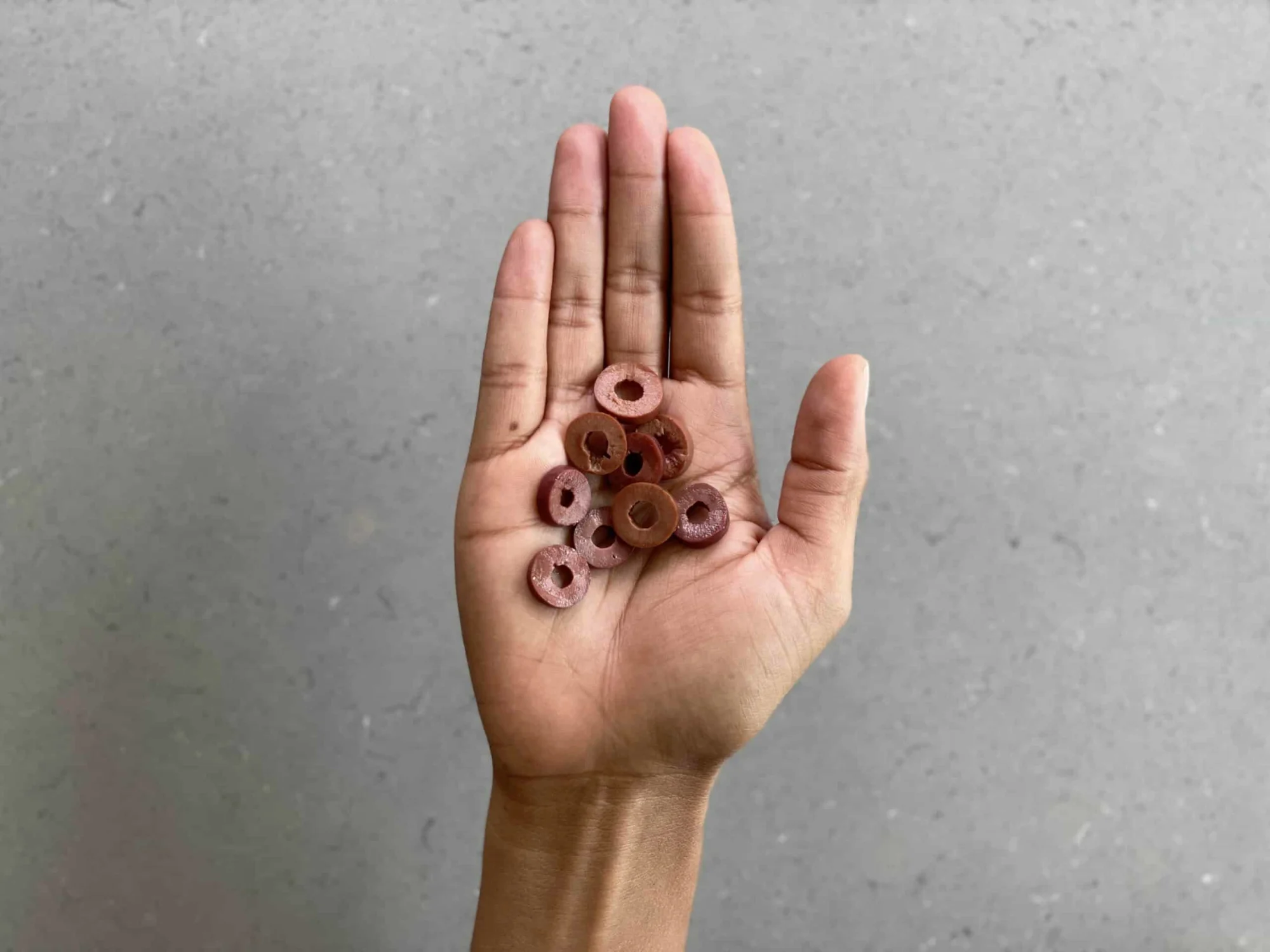 a hand holding a small pile of kalamata olives sliced into rings for children 12 months+