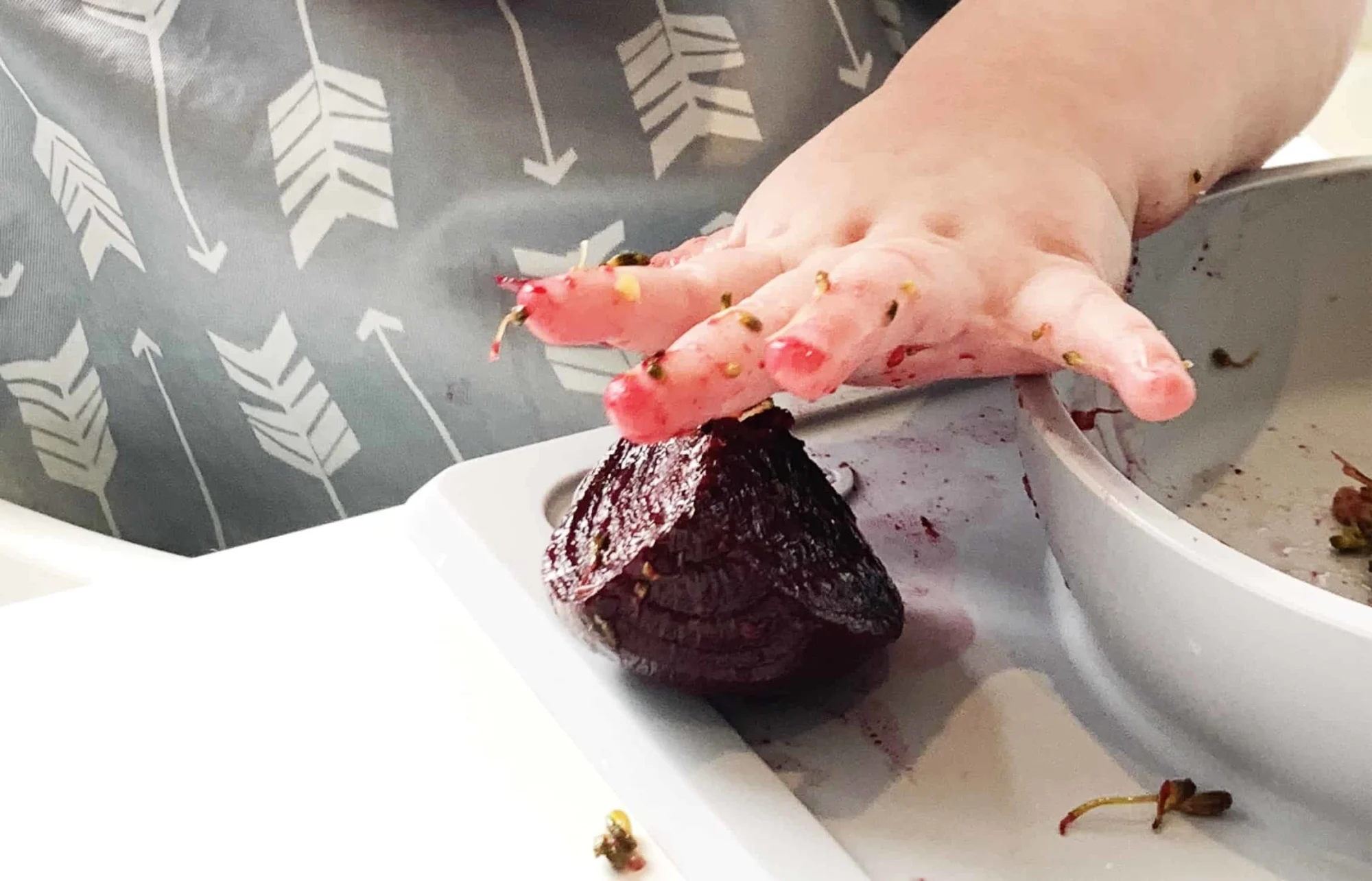 a baby reaches for a large beet