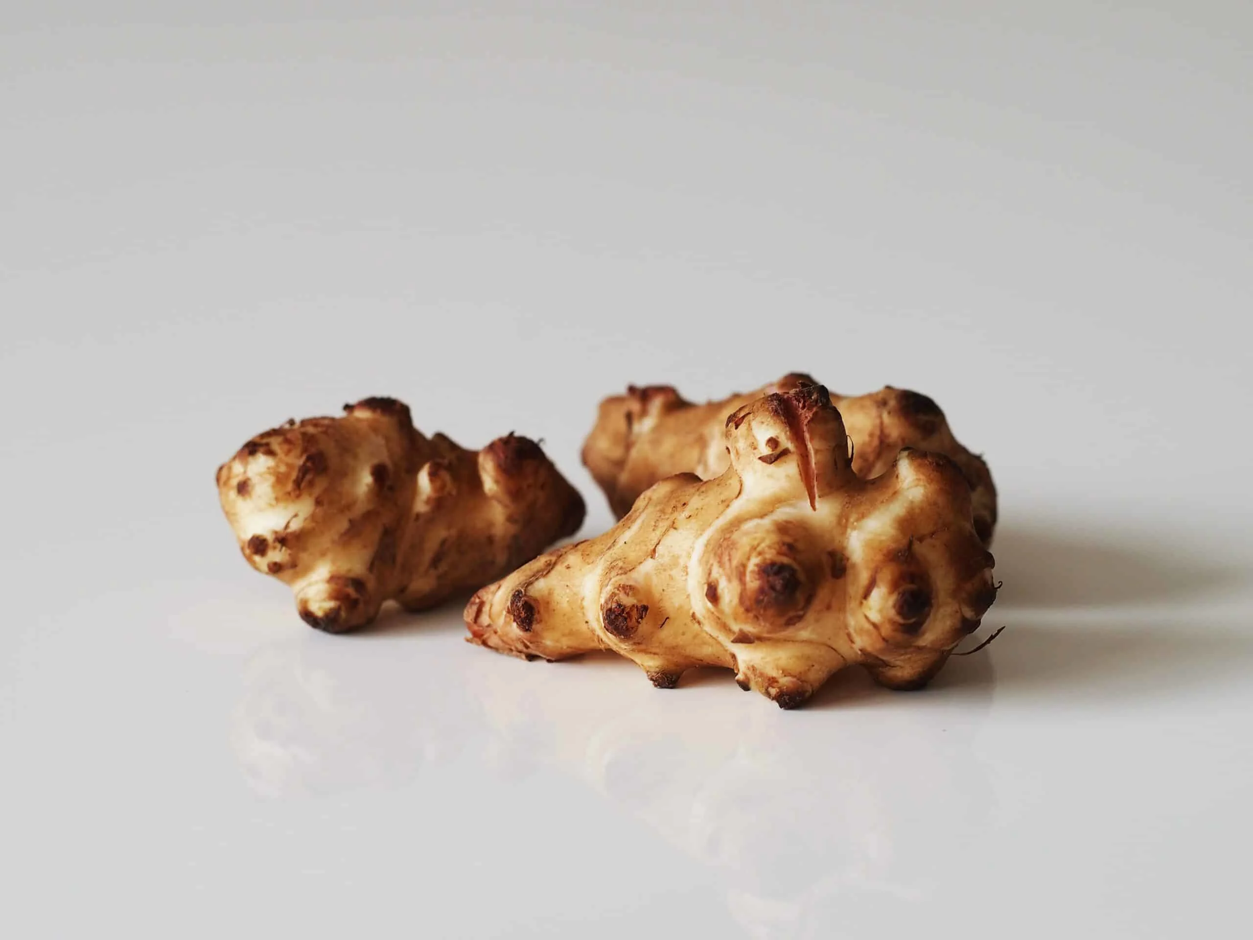 two whole raw sunchokes on a beige background for babies starting solids