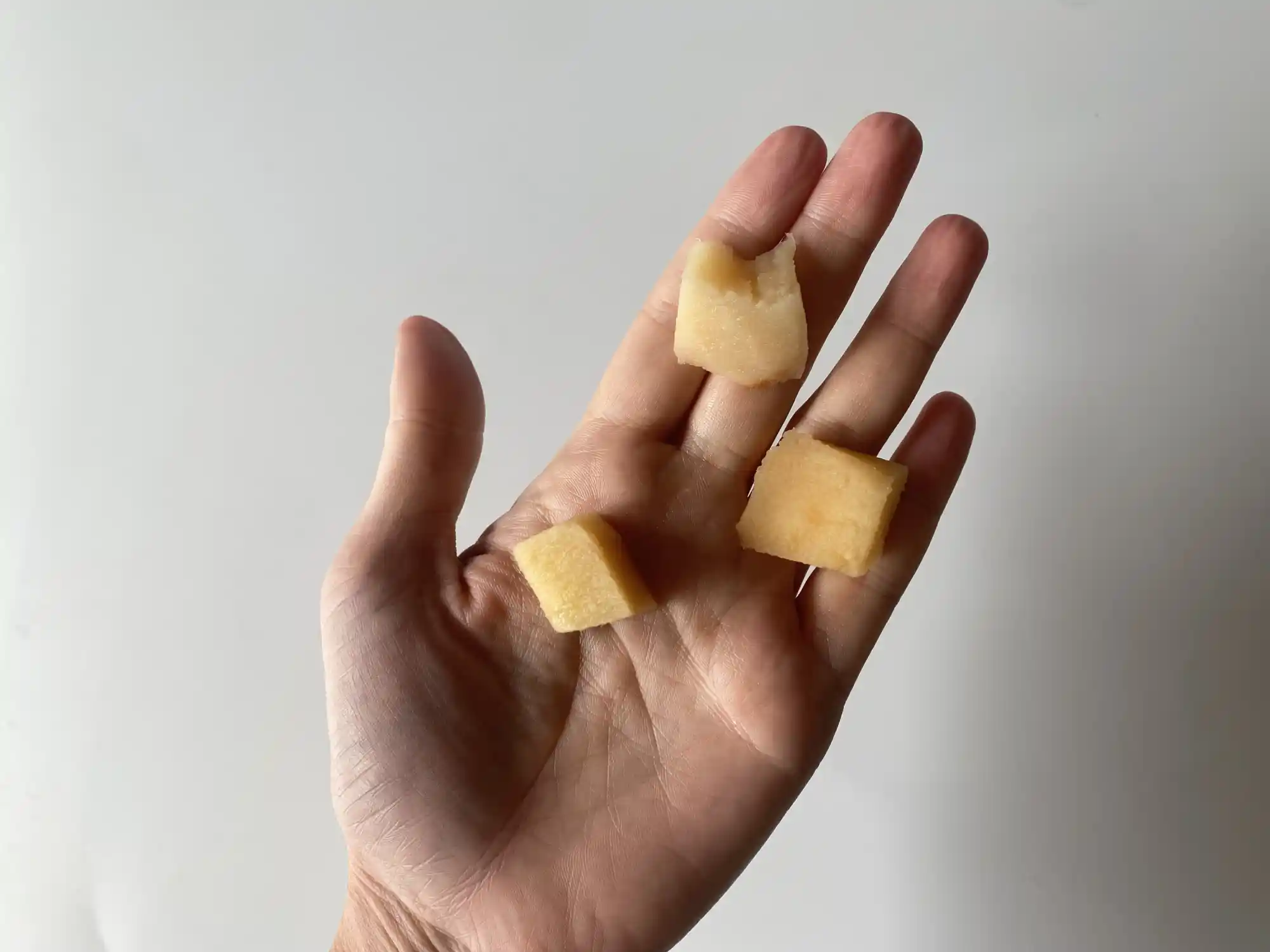 a hand holding three bite-size pieces of quince that have been cooked until soft