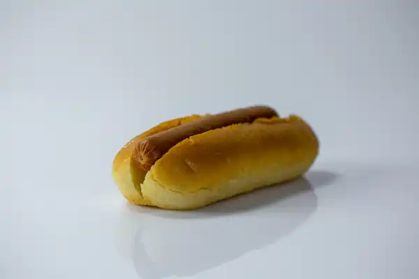 one whole hot dog in a bun on a white background