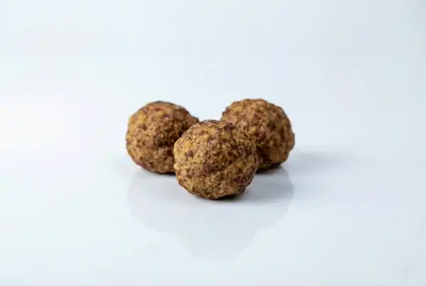 a photograph of 3 whole cooked meatballs on a white background