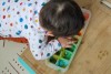 a baby hovers over his edible finger paints and tastes them