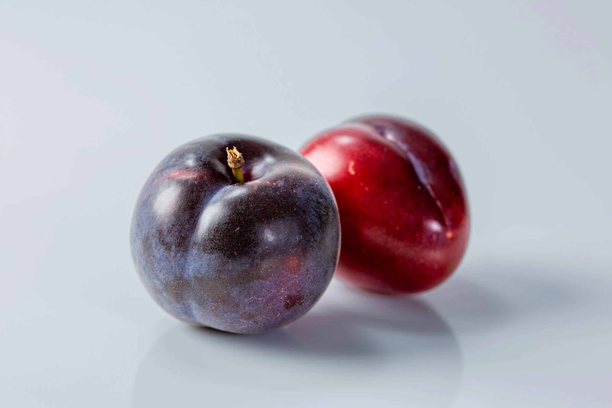 Two whole raw plums before they have been prepared for a baby starting solid foods