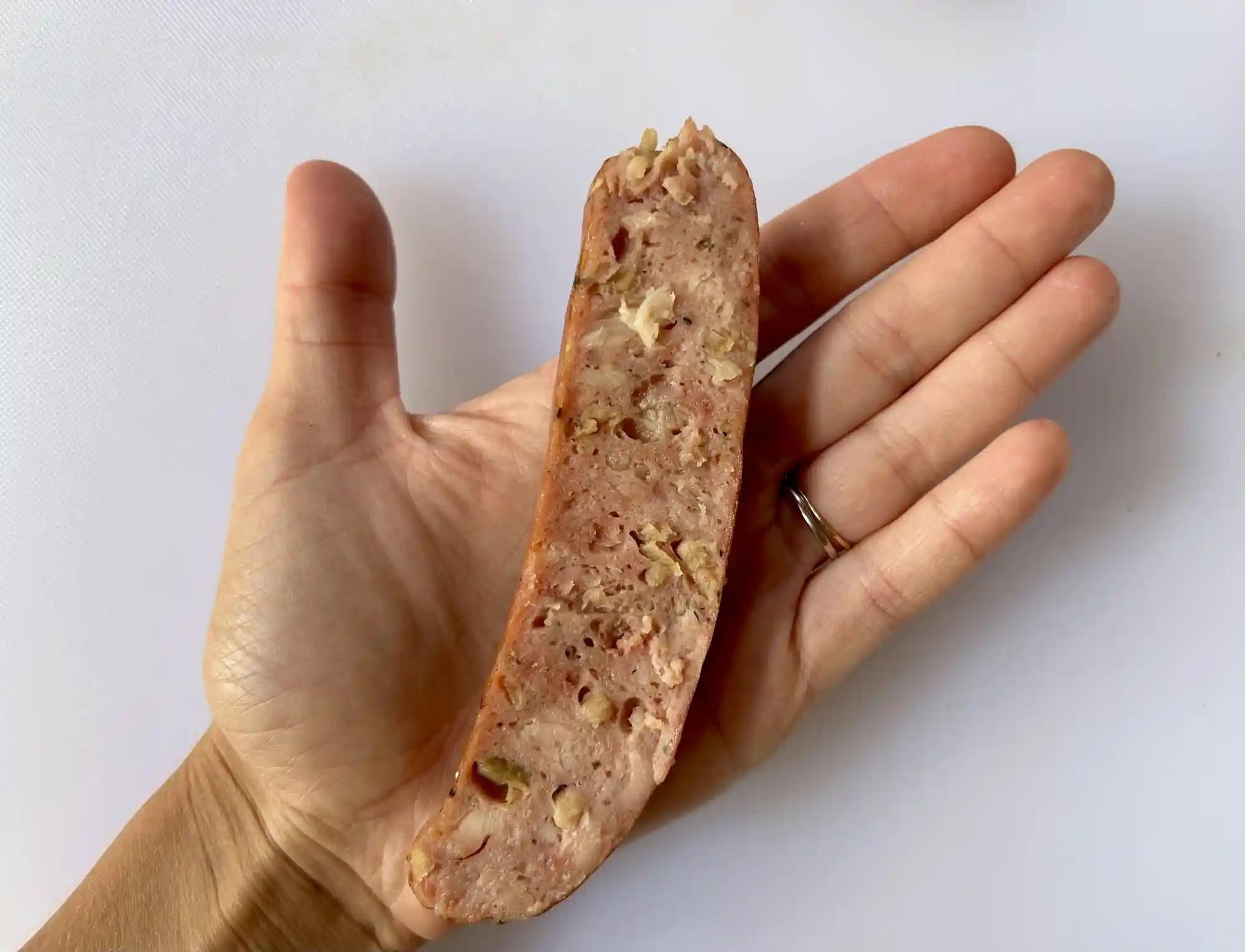 a photograph of a hand holding a sausage halved lengthwise