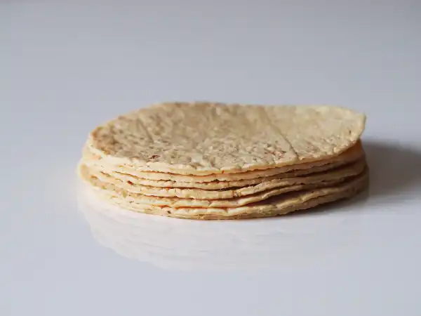 a photograph of a pile of soft corn tortillas on a white background