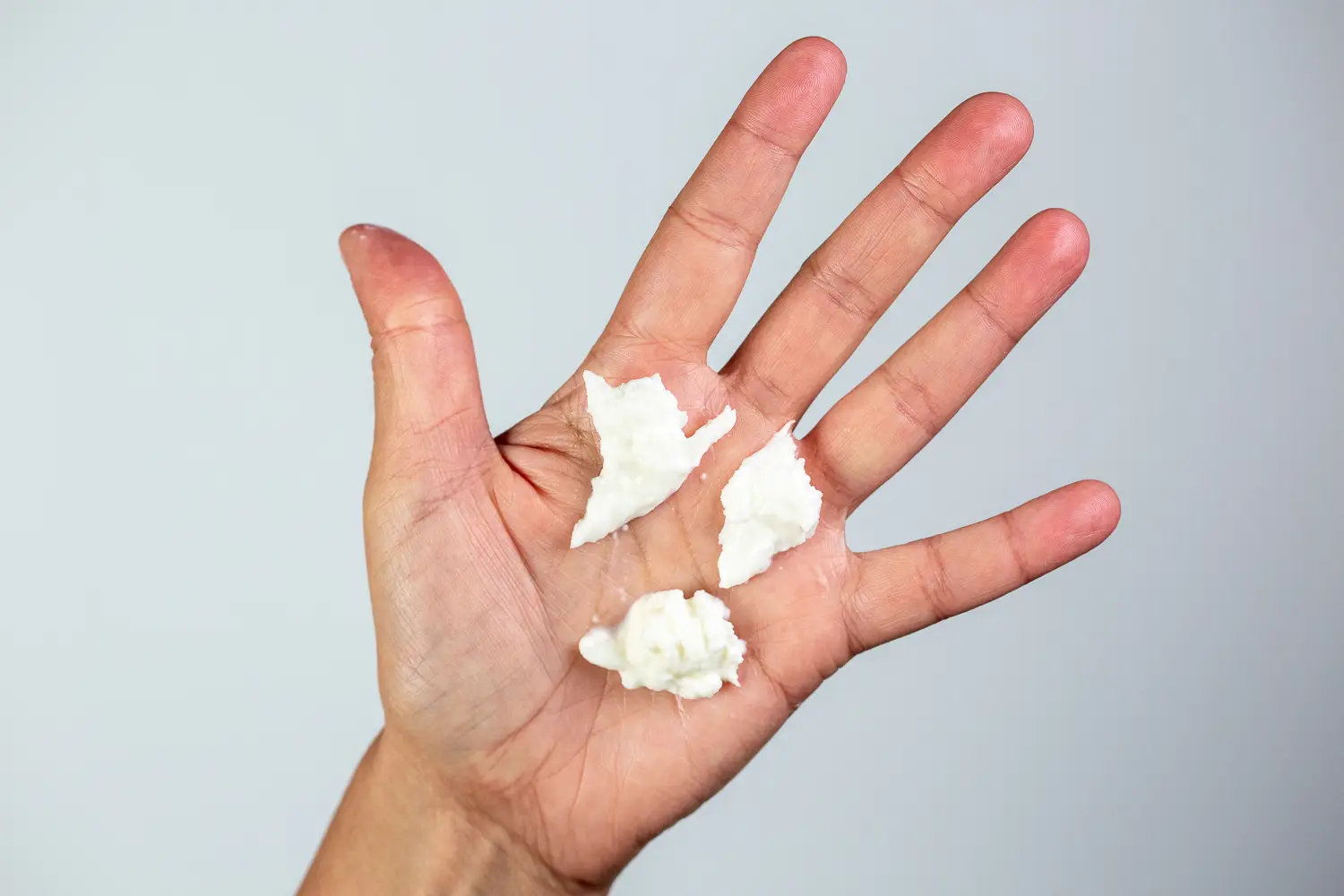 a hand holding three bite-sized pieces of burrata