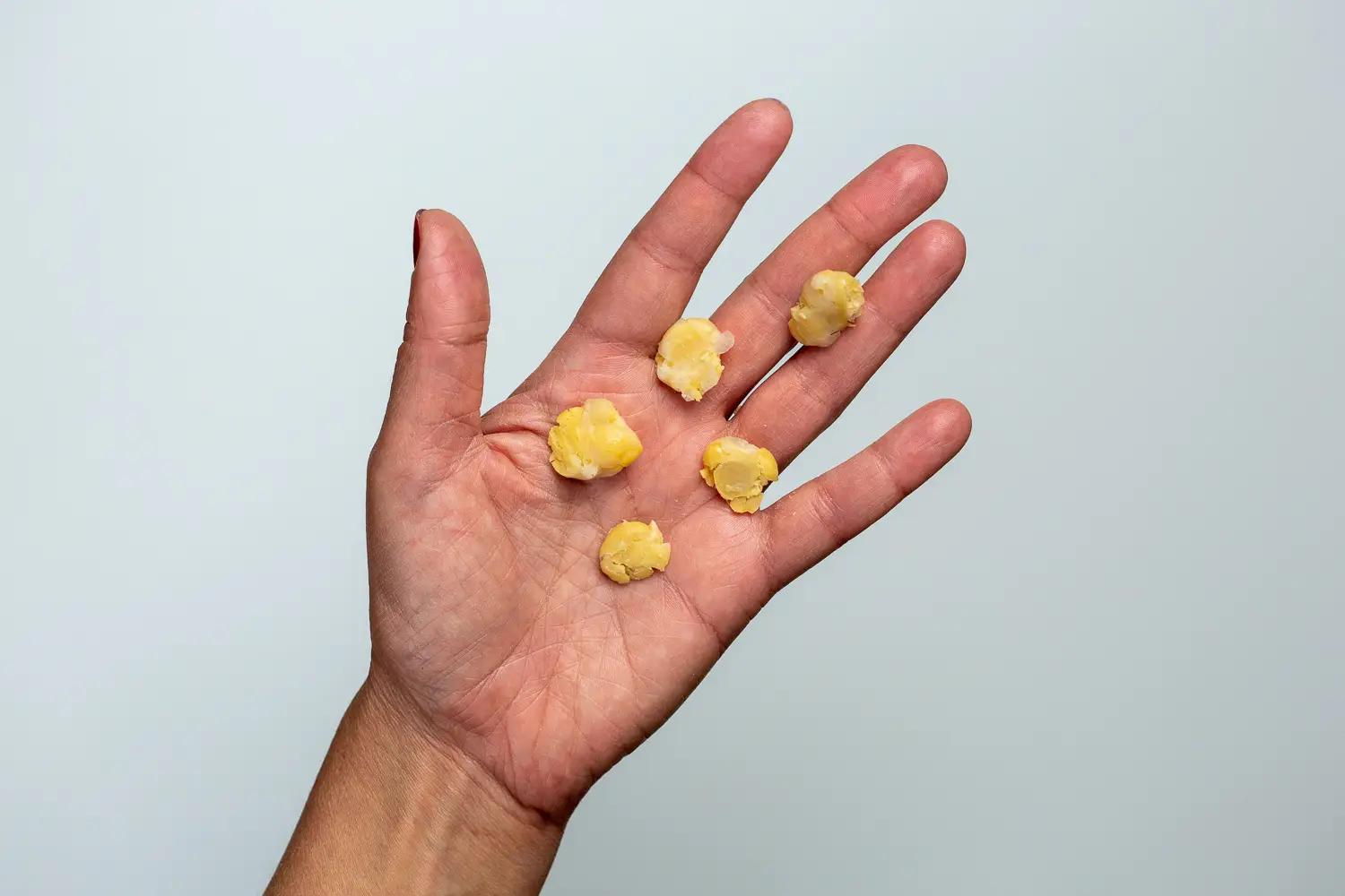 a hand holding five flattened chickpeas for babies 9 months+
