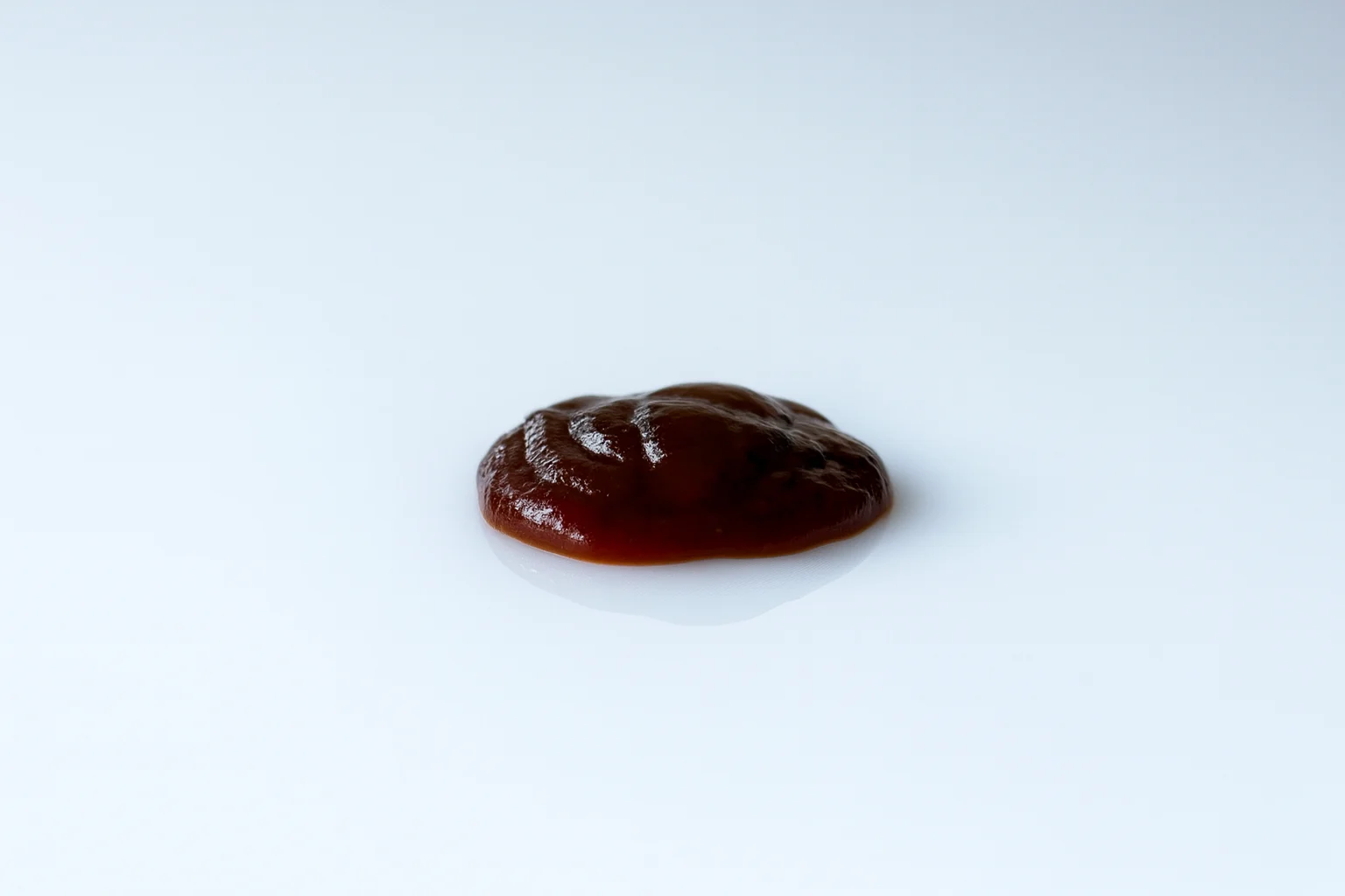 a photograph of a blob of barbecue sauce on a white background