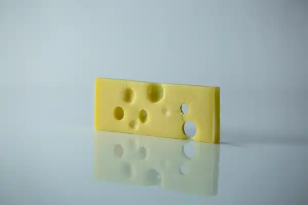 a thin slice of emmentaler cheese standing vertically on a white background