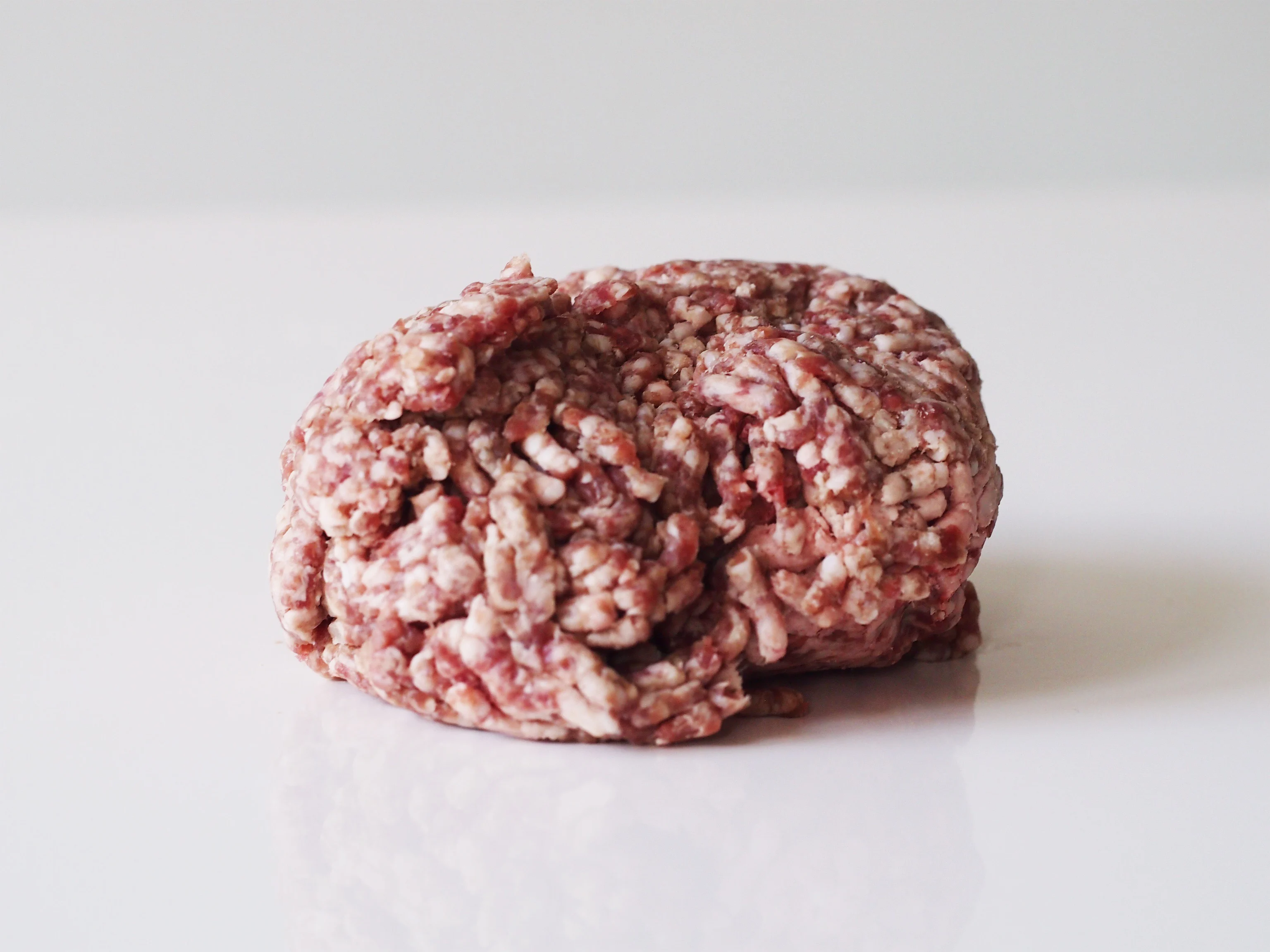 a photograph of a small amount of raw ground lamb on a white background