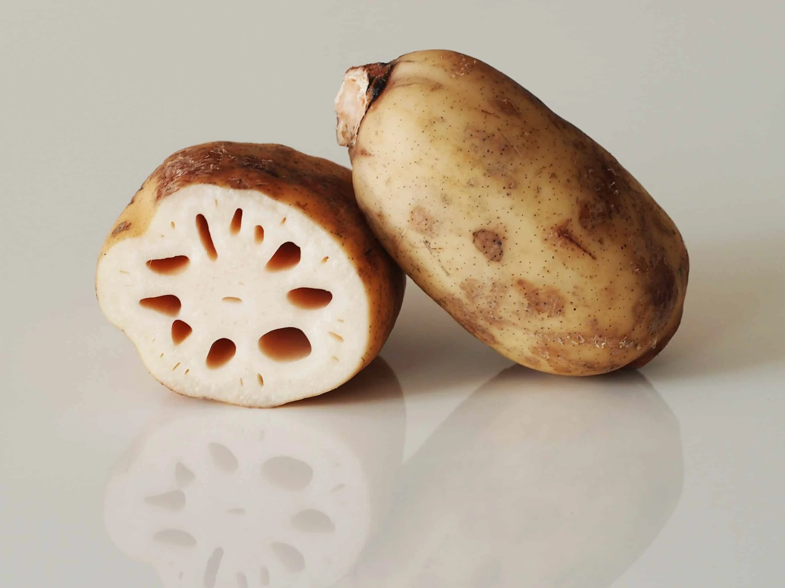 a whole lotus root propped on a lotus root cut in half ready to be cooked for babies starting solids