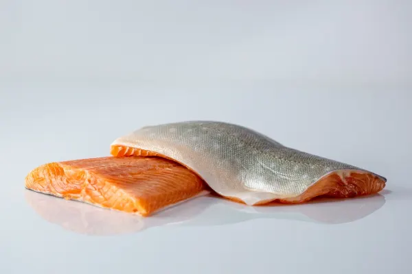 a photograph of two raw filets of arctic char, one with skin side up, on a white background