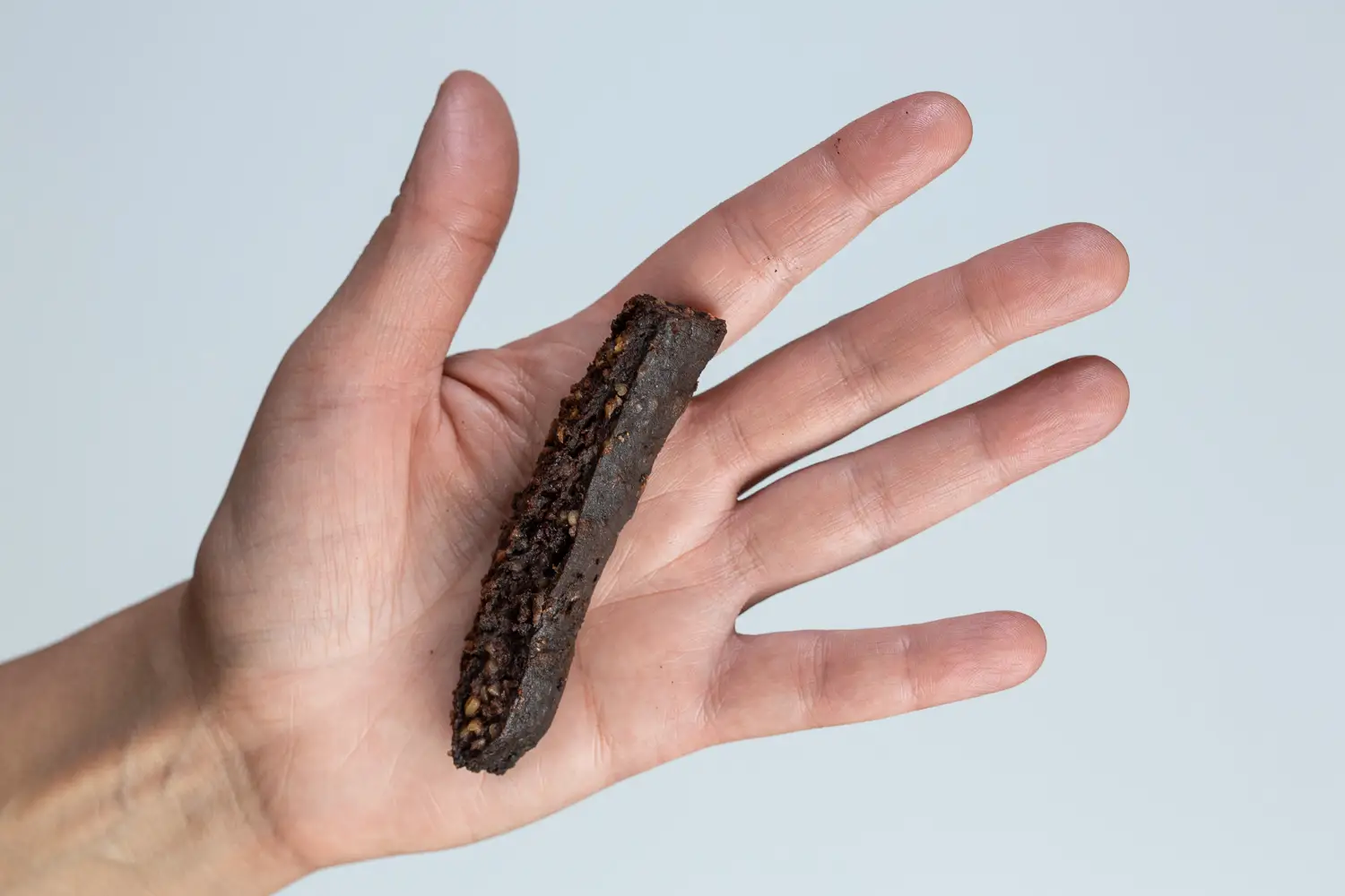 a hand holding a blood sausage quartered lengthwise