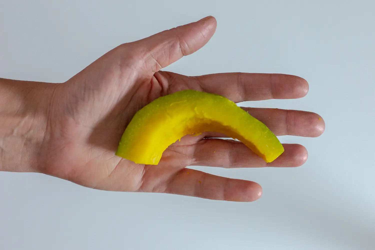 a hand holding a cooked spear of kabocha squash 