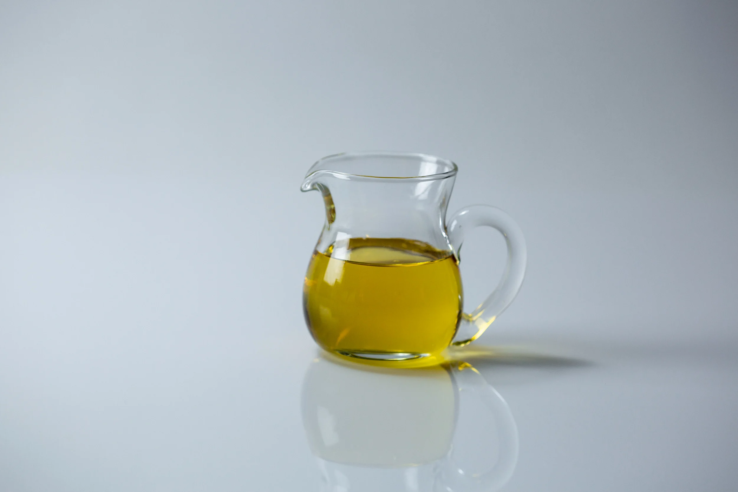 a photograph of a small glass pitcher of agave syrup on a white background