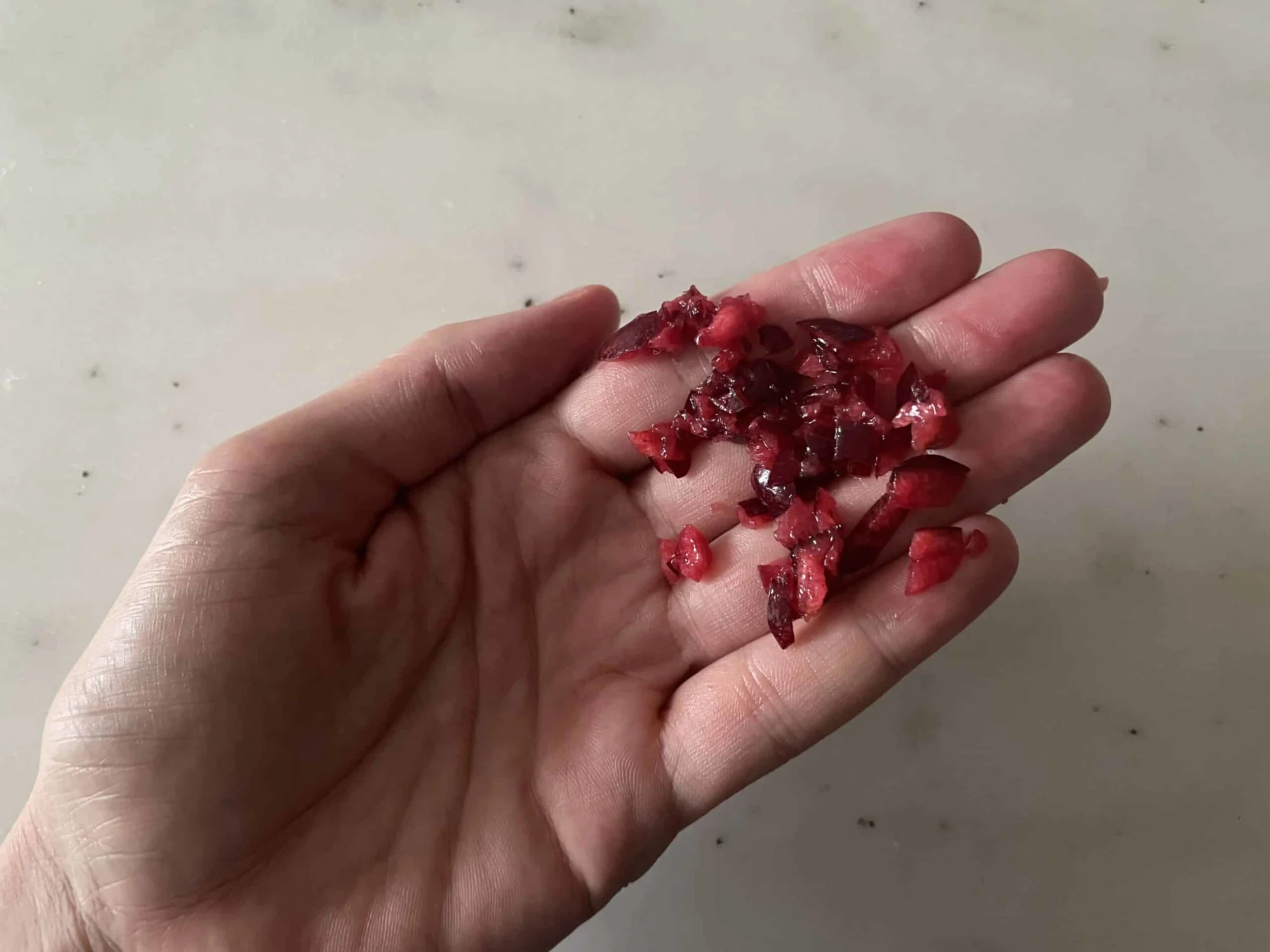 a photograph of a hand holding minced cherry for young babies