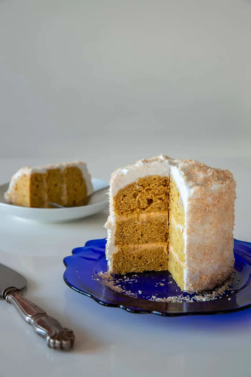 A cut citrusy squash cake reveals three golden layers with pale frosting.