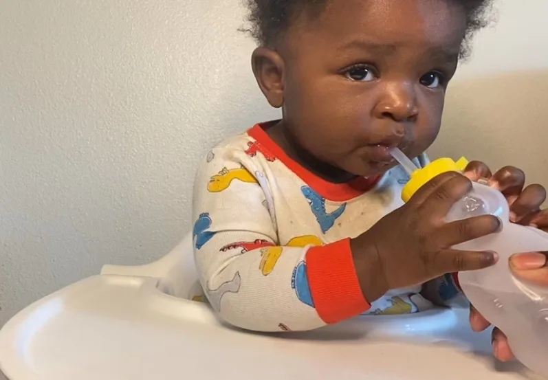 a photograph of a baby drinking from a honey bear straw trainer cup