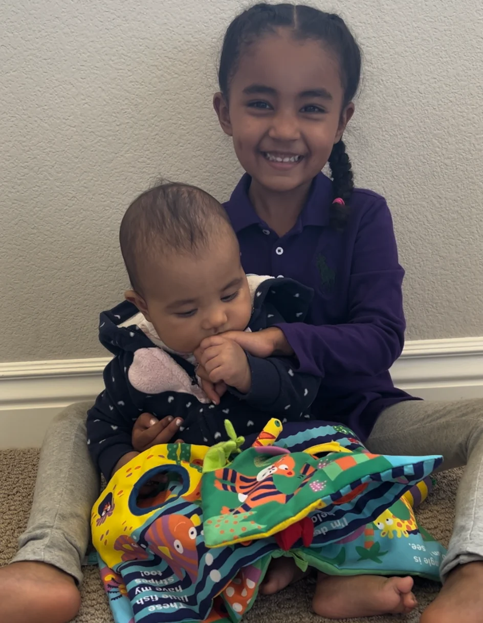 Maya 5mo sucks on her sister's hand