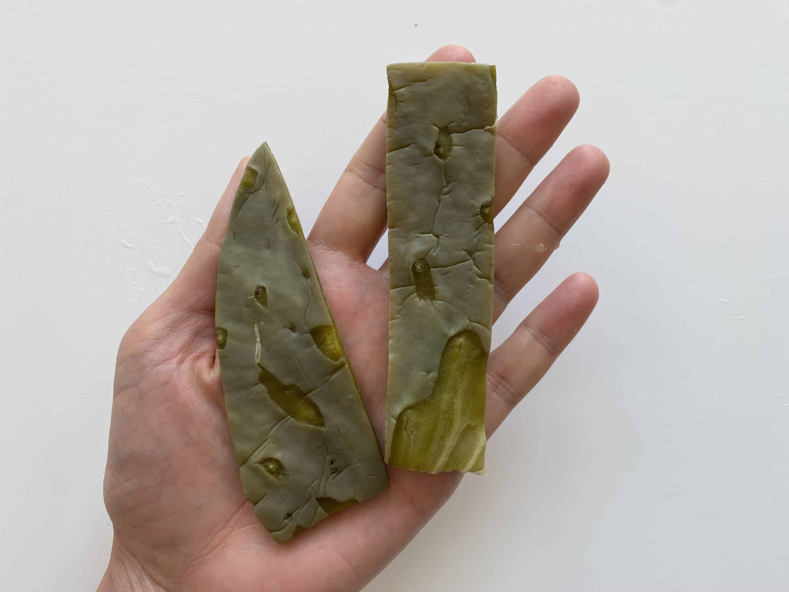 a hand holding two cooked strips of nopales for babies 6 months+