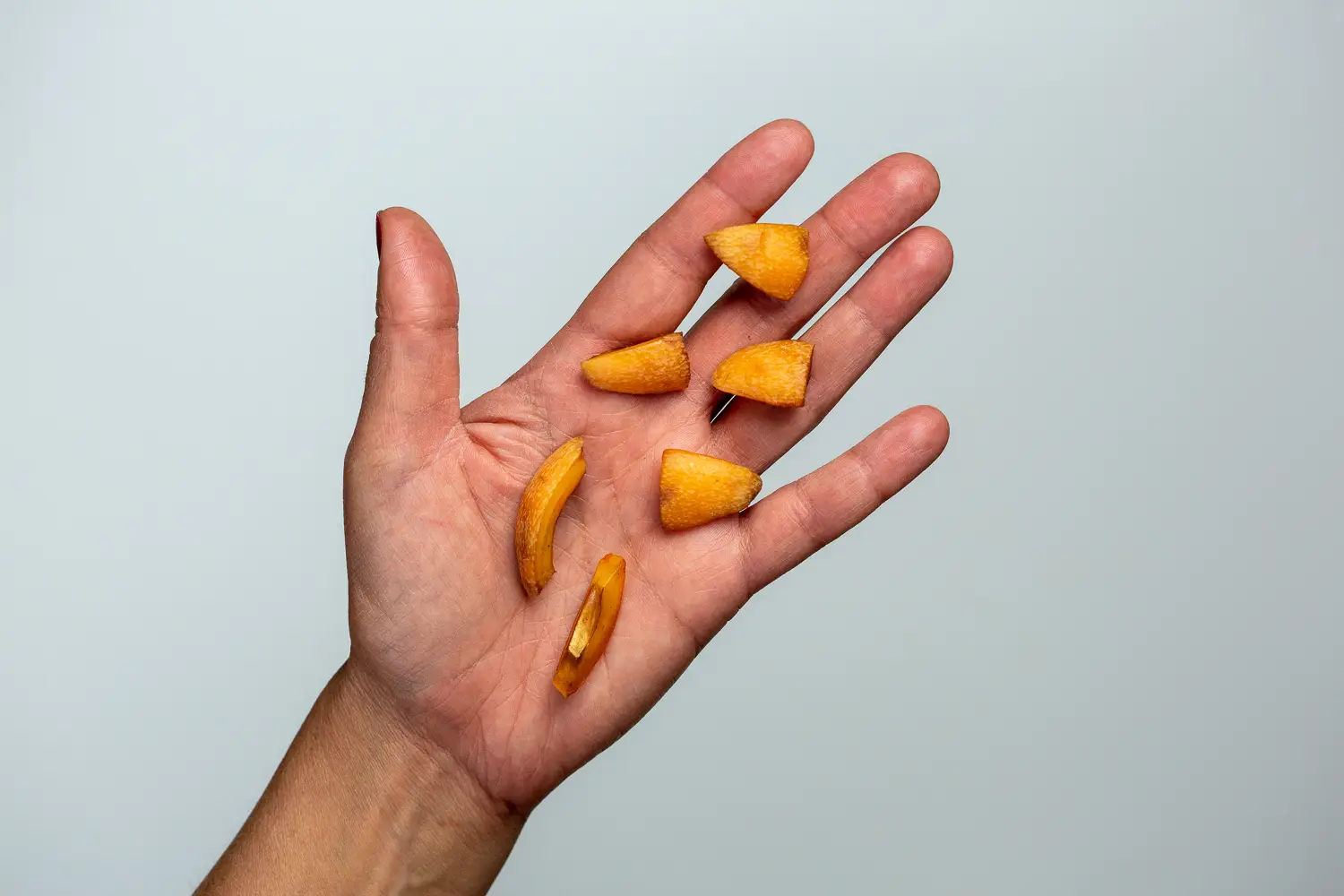 a hand holding six bite-sized pieces of ripe loquat for babies 9 months+