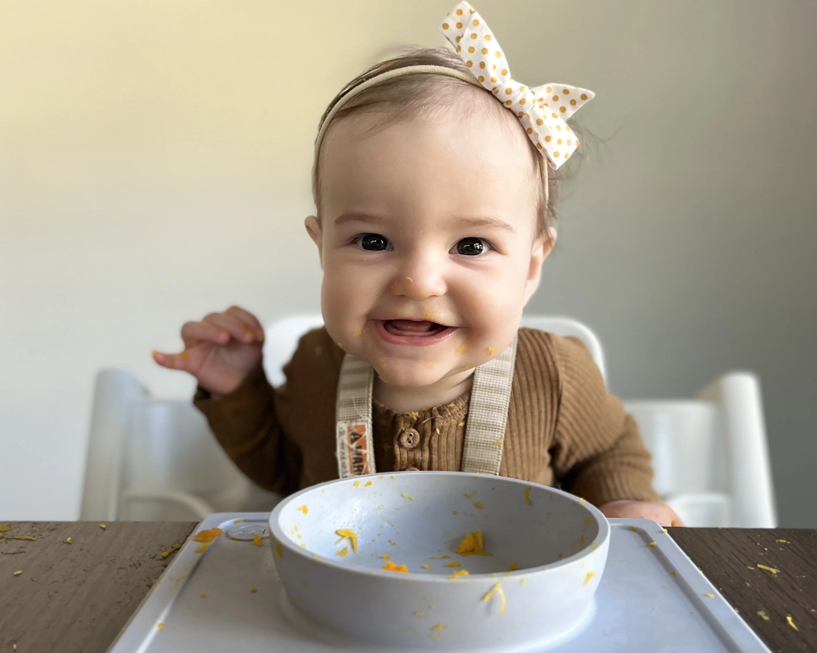 6-month-old in highchair smiles at the camera