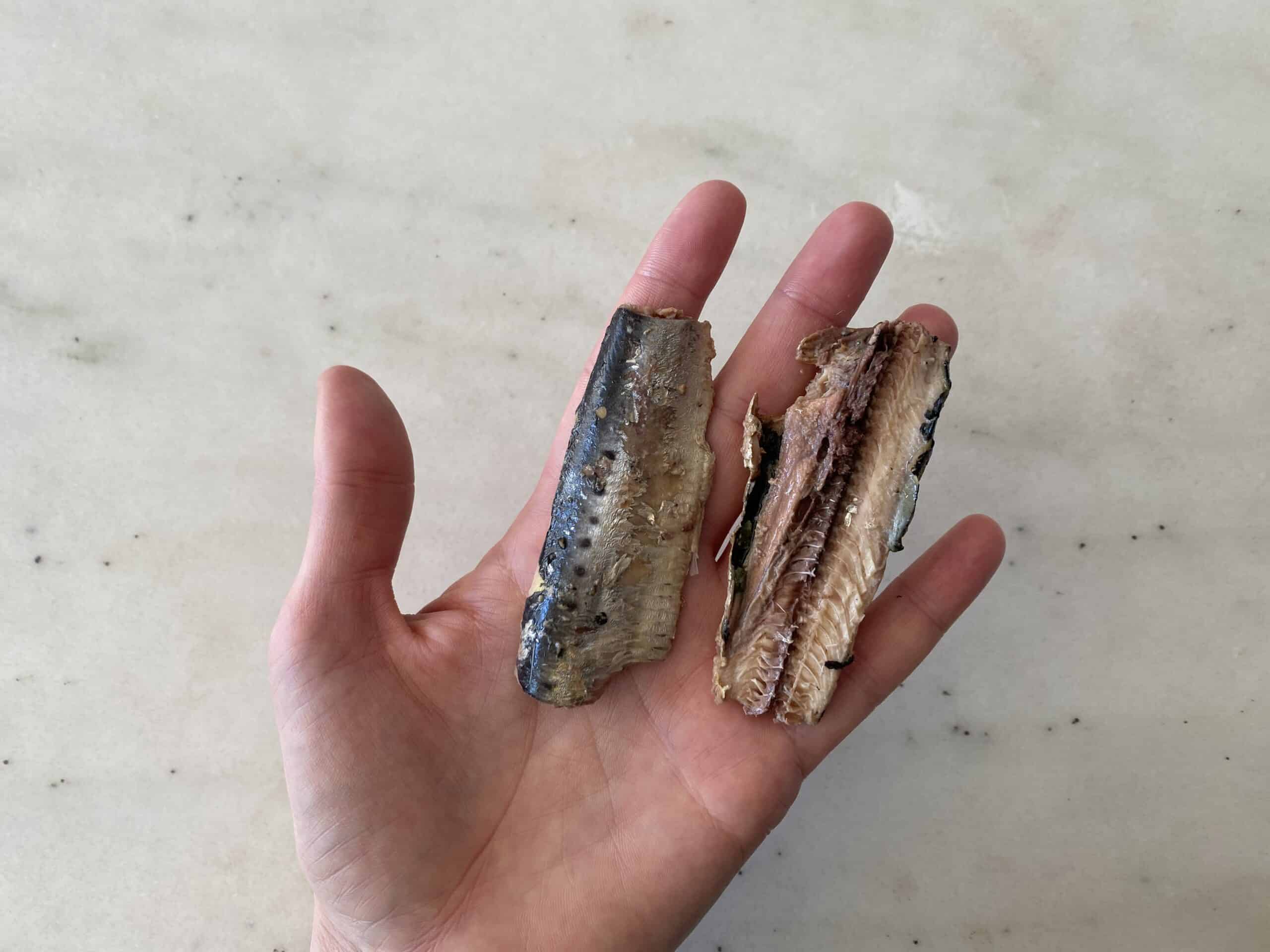 a hand holding a canned sardine fillet for babies 6 months+