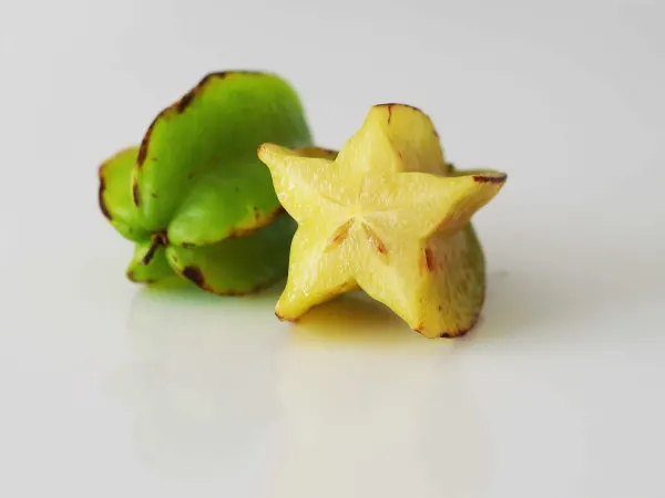 2 star fruits, one yellow and one green, one cut open before being prepared for babies starting solids