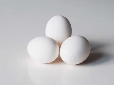 a photograph of three whole, raw eggs on a white background