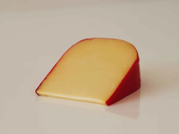 a wedge of gouda cheese with a red wax rind ready to be prepared for babies starting solids