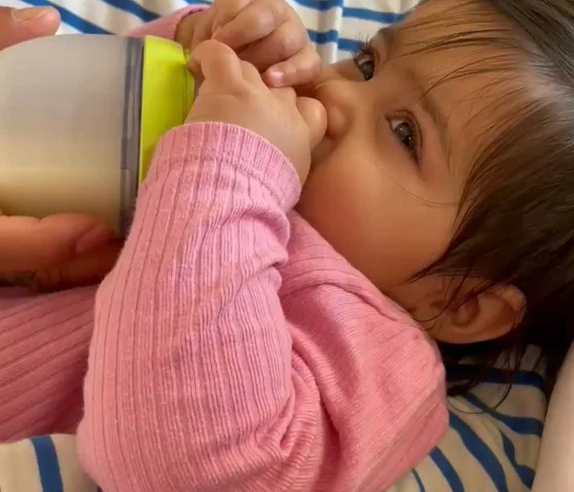 a photograph of a baby drinking from a baby bottle