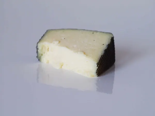 a wedge of manchego on a plain background