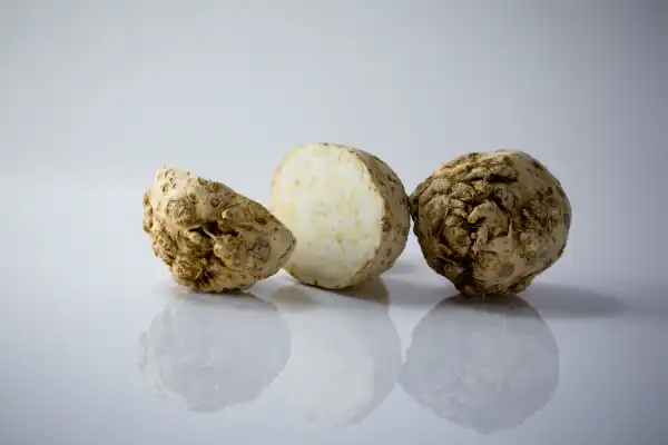 two raw celery roots, one cut in half and one whole