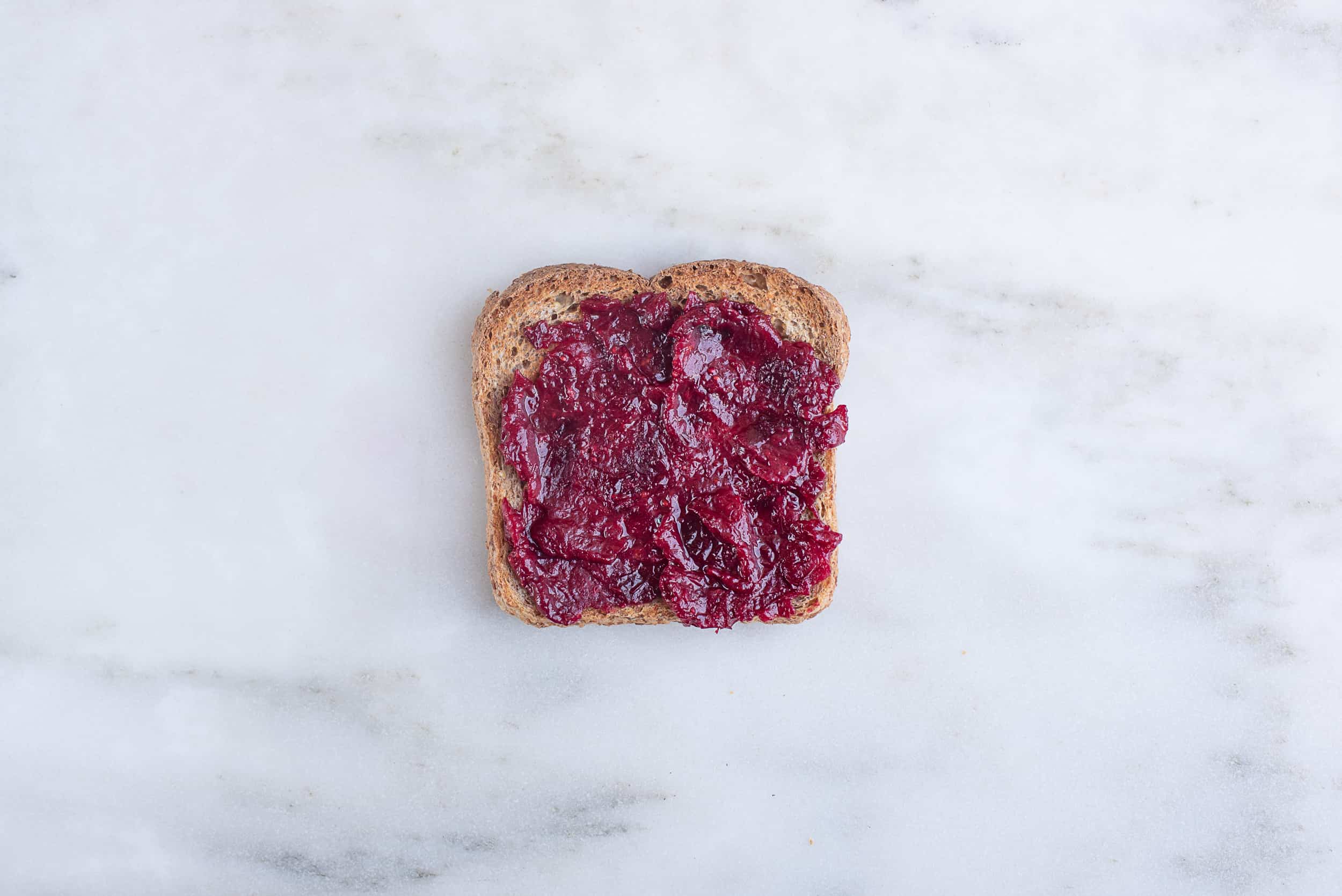 piece of toast topped with cranberry sauce, sitting on a countertop