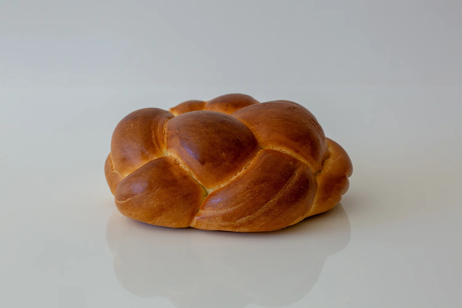 a photograph of a whole loaf of challah on a white background