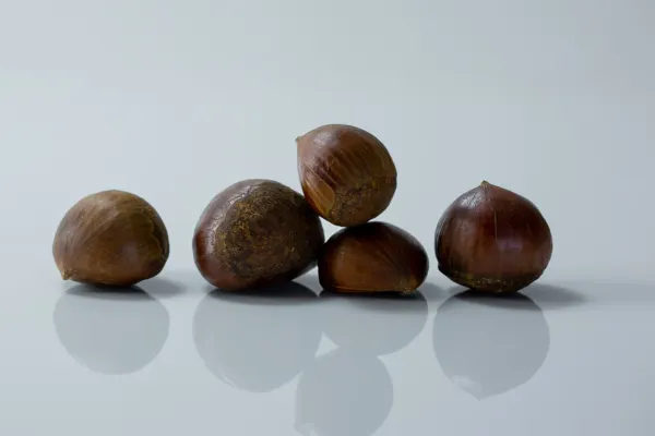 five whole unpeeled chestnuts on a white background