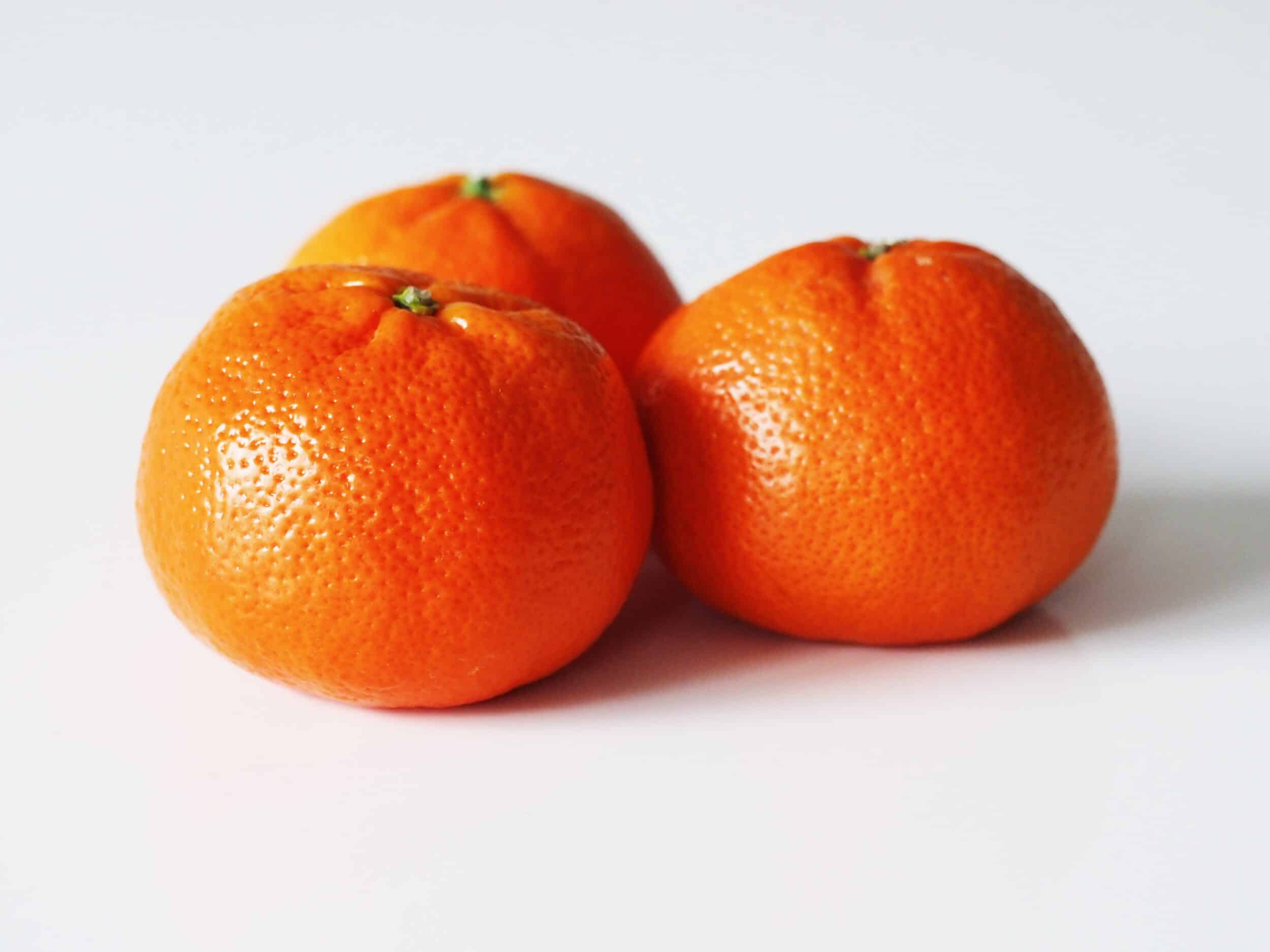Three vibrant clementines on white background