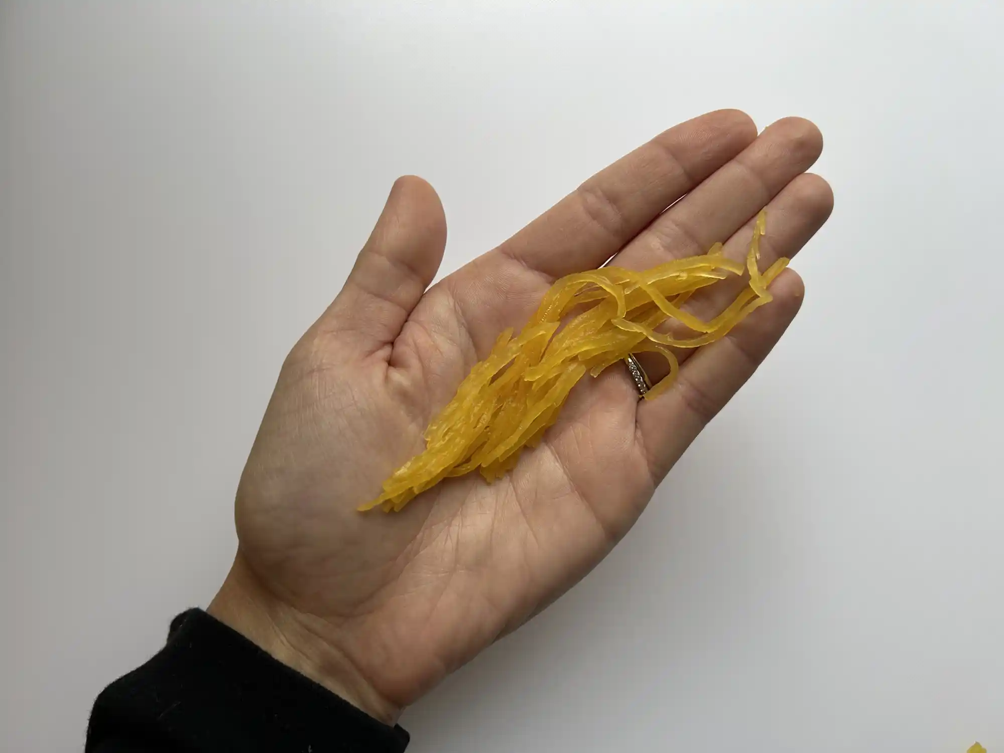 a hand holding long strands of cooked spaghetti squash