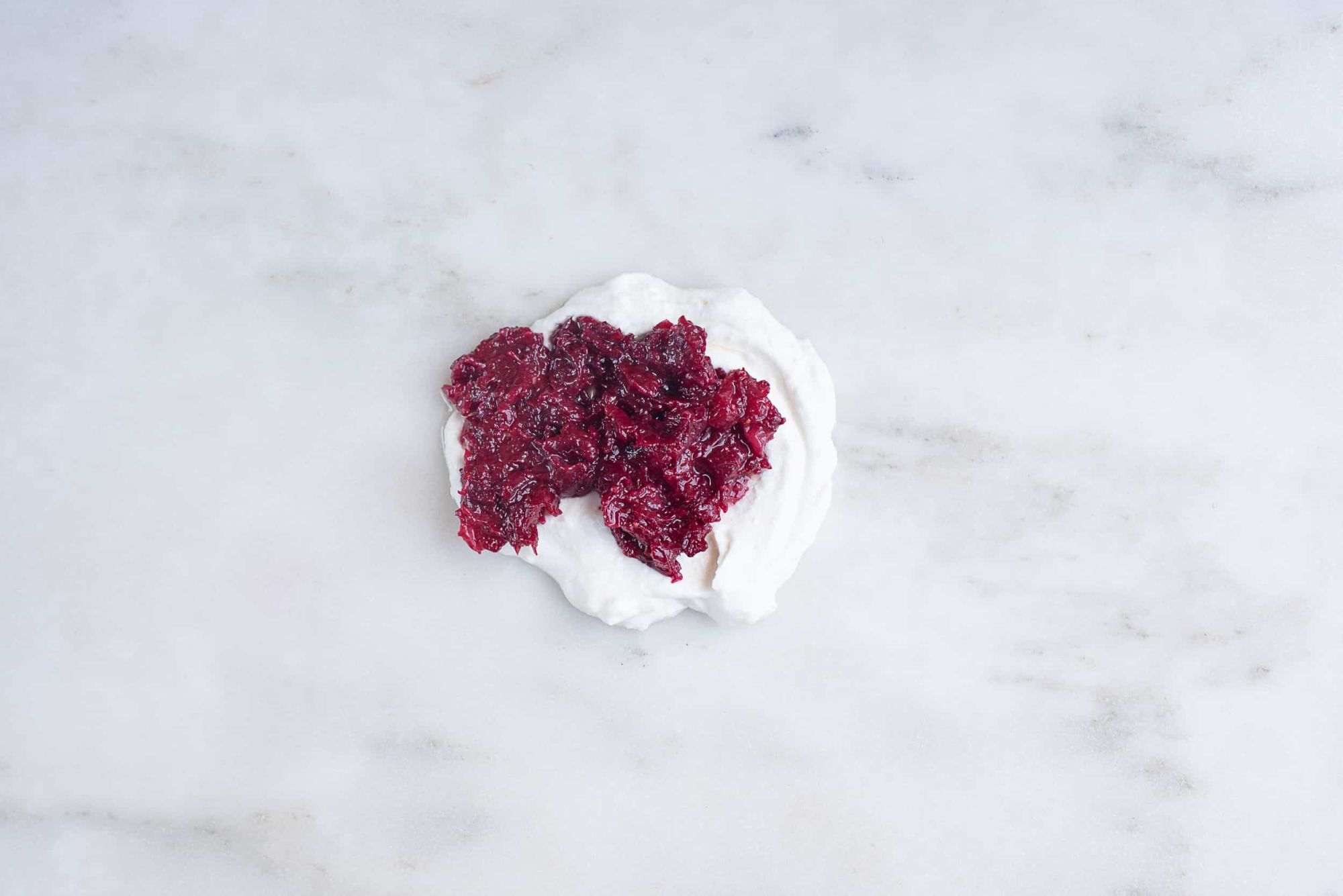 pile of ricotta cheese topped with cranberry sauce, sitting on a countertop