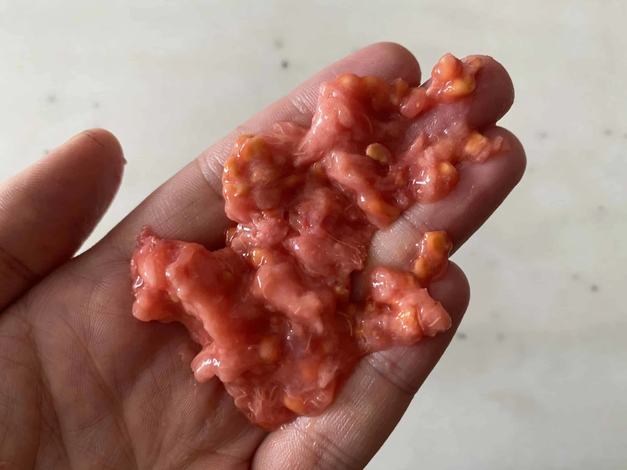 The mashed flesh of a pink guava with seeds.