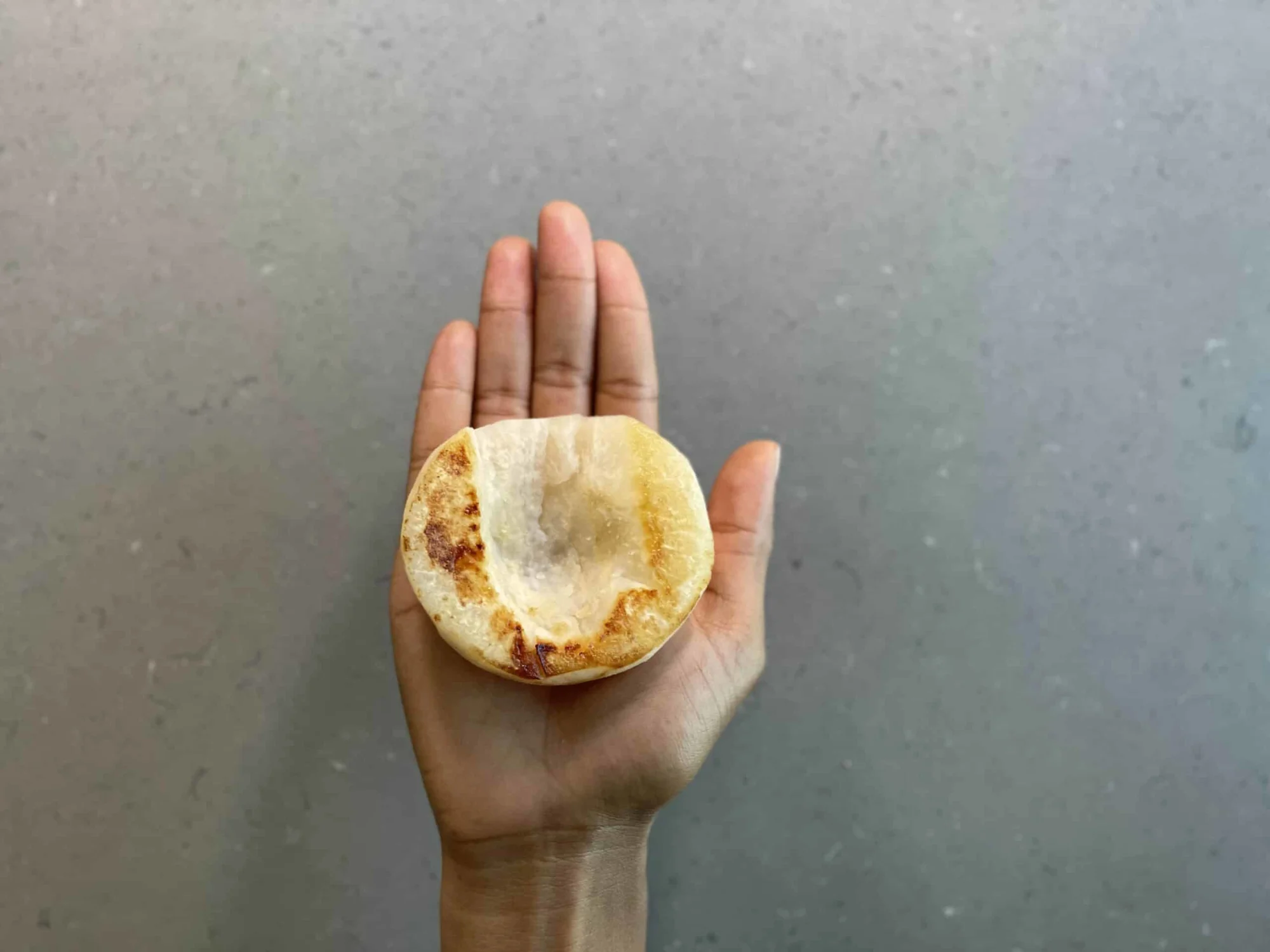 a hand holding half of a cooked Asian pear for babies 6 months+