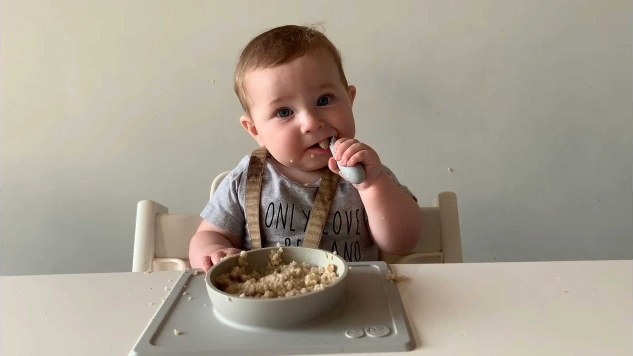 a photograph of a baby feeding himself oatmeal with a spoon