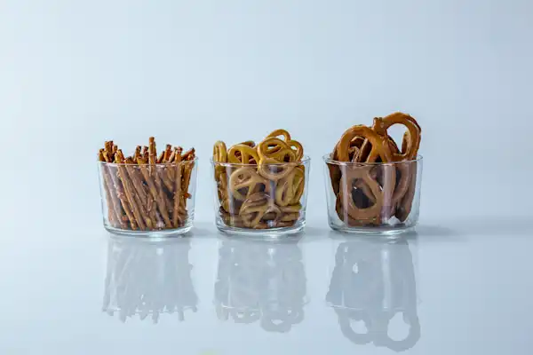 When can babies have hard pretzels a photograph of three clear cups with different kinds of hard pretzels in them